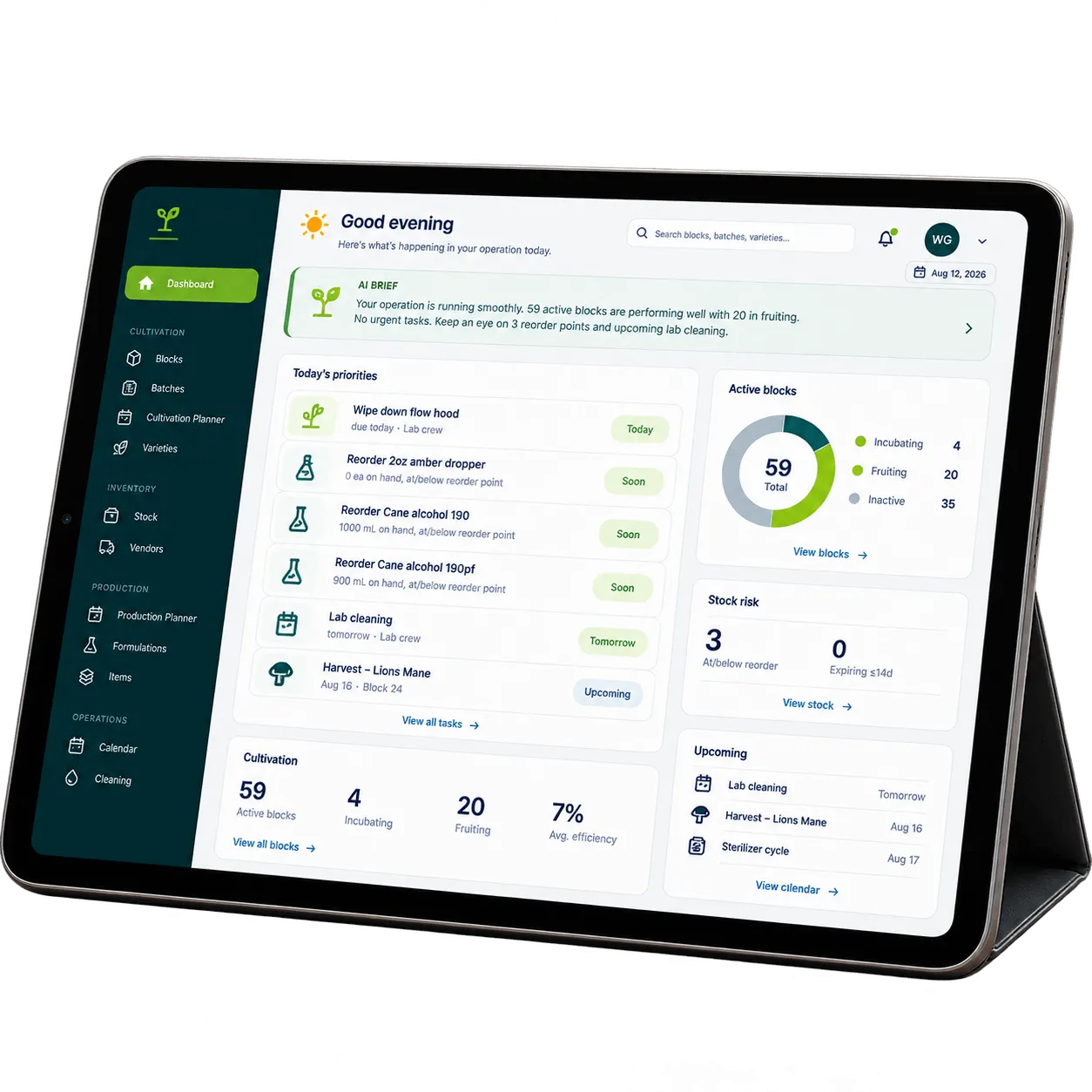 A tablet on a workbench in a mushroom grow room showing the GrowGrid dashboard — today's priorities, active blocks by stage, stock risk, and upcoming tasks.