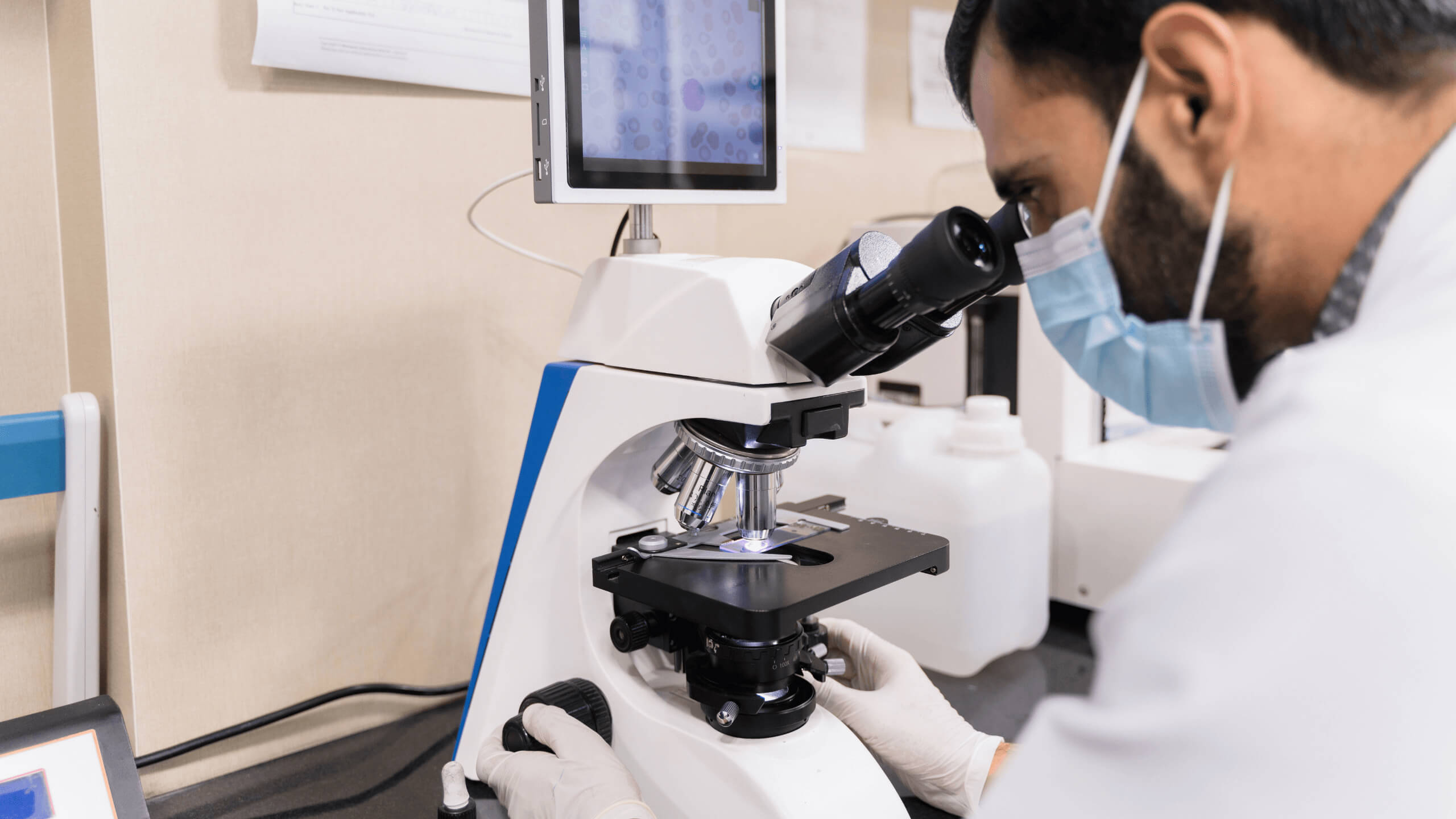 Middle-aged virologist looking through microscope in lab